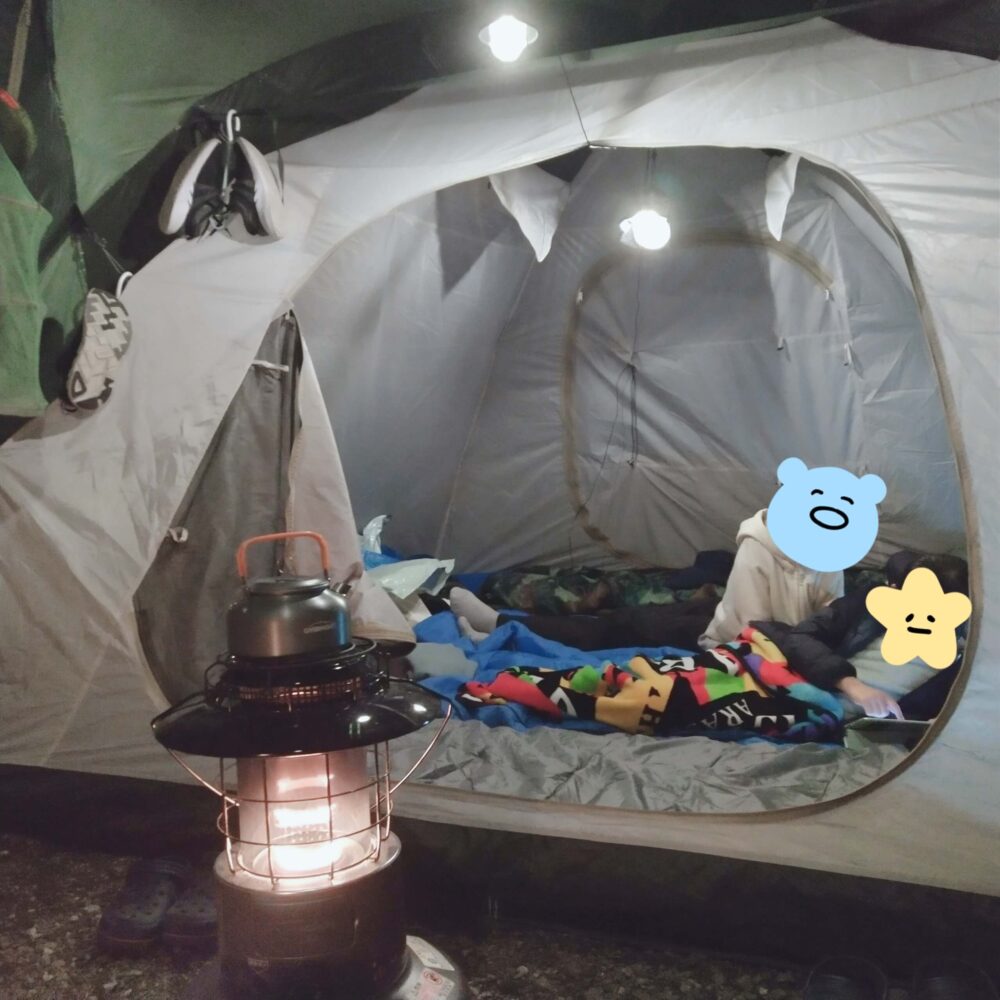 キャンプでテント内で子供たちが動画鑑賞している写真です。